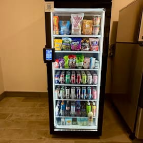 Smart cooler with a card reader placed against the wall of a quiet apartment hallway