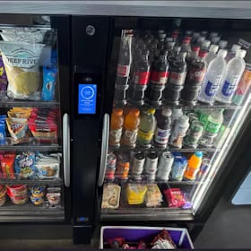Two smart coolers side by side, snacks in the left door and drinks in the right, with a card reader screen between them
