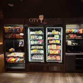 Two glass-front coolers plus an open snack shelf and checkout screen built into the wall of a pickleball club