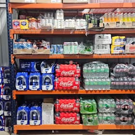 Warehouse club racking stacked with cases of soda, sparkling water and bottled drinks